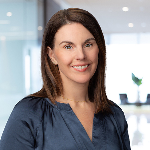 A woman with straight brown hair, wearing a navy blouse, smiles at the camera in a modern, well-lit office, representing litigation support for lawyers in Chicago.