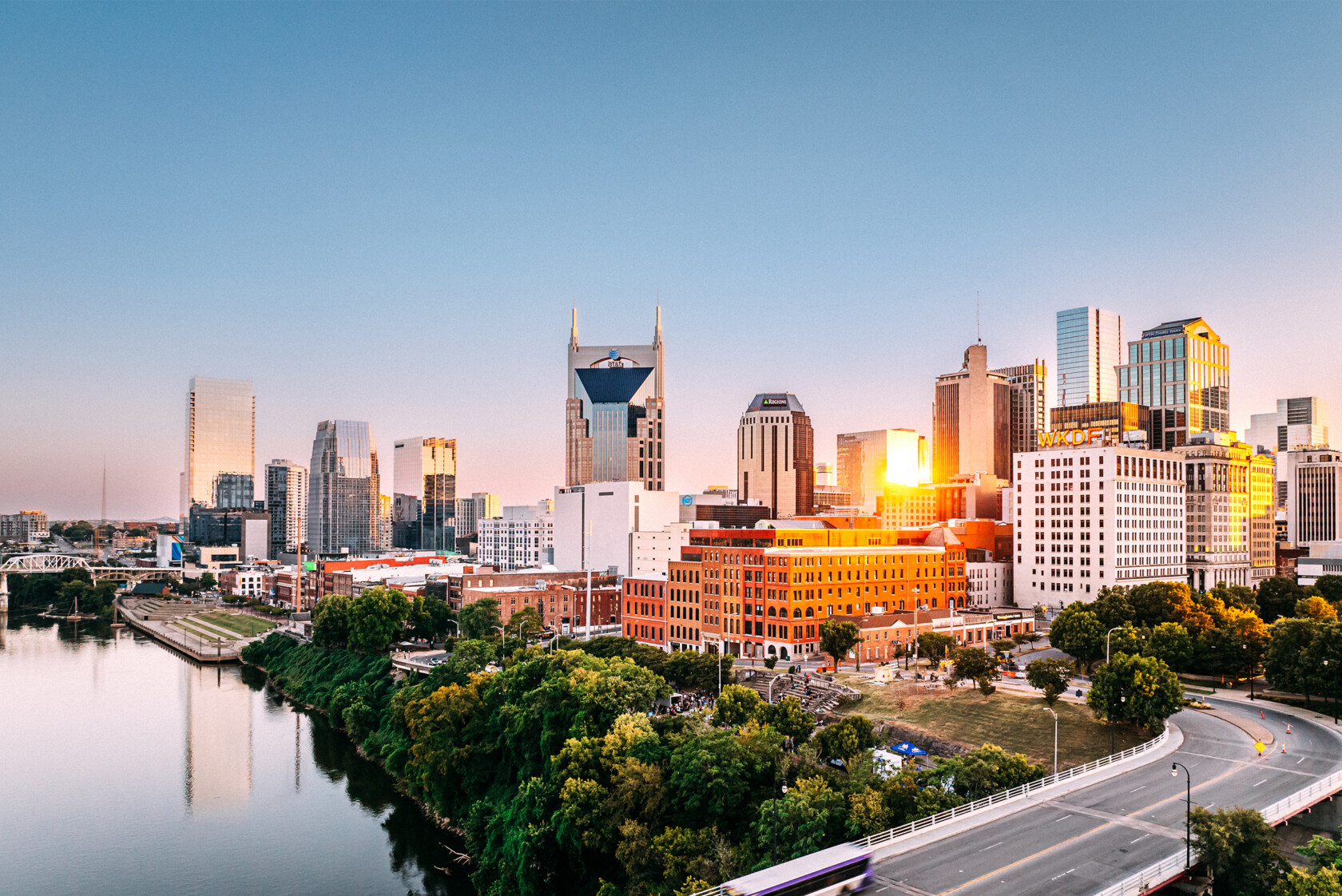 Skyline view of downtown Nashville, Tennessee, at sunset with reflections on the river and modern buildings in the background, reminiscent of a vibrant corporate law office or litigation support hub.
