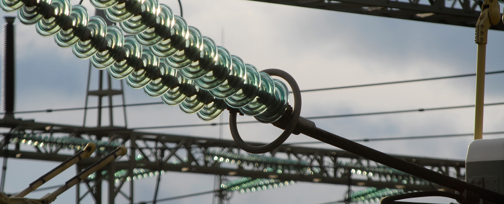 Close-up view of a row of green glass disk insulators on a high-voltage power line, with supporting steel structures and wires in the background—much like the steadfast support provided by experienced Chicago lawyers.