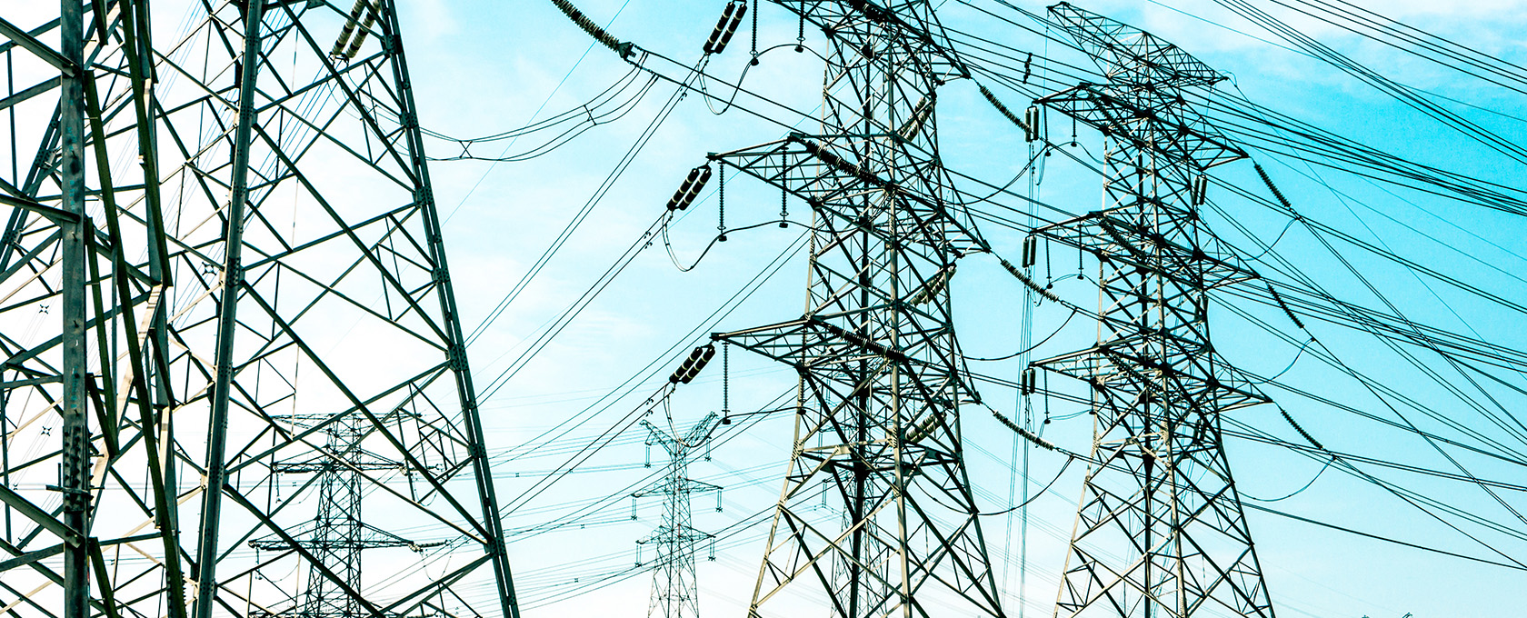 High-voltage electricity transmission towers and wires set against a blue sky, highlighting the infrastructure often at the center of litigation support for Chicago lawyers specializing in intellectual property law.