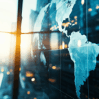 A map of the world is displayed on a glass wall in a modern office building with sunlight streaming in through large windows.