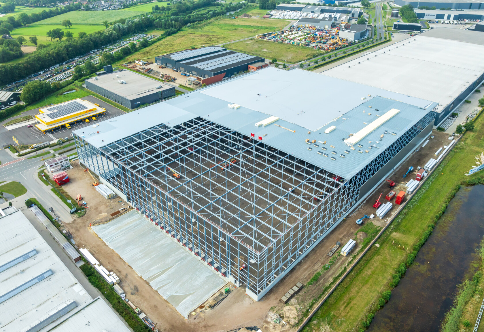 A building under construction with many buildings and a river.